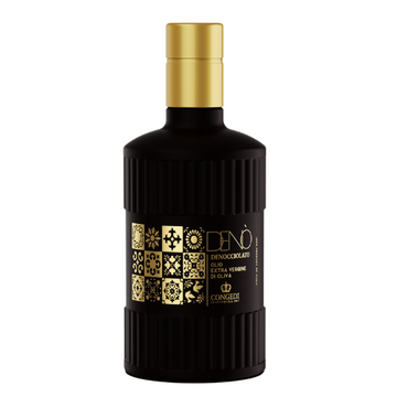 Matzwarte geribbelde fles met gouden dop. Etiket met zwart-gouden tegelpatroon in mozaïekstijl en de tekst Denò Denocciolato, olio extra vergine di oliva.